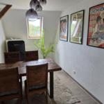 Esszimmer mit Holztisch, Stühlen, Kühlschrank und Wandplakaten.