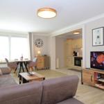 Living room with sofa, TV, and kitchen area in the background.