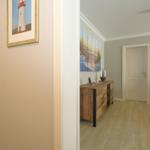Hallway with wall art and door to living room with wooden cabinet and sofa.