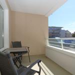 Balcony with table and two chairs, view of parking lot and buildings.