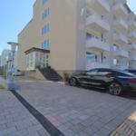Modern apartment with balcony, parking space, and entrance area. Building with multiple floors.