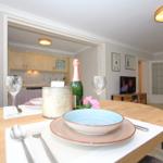 Dining table with plates, cutlery, and bottle. Kitchen and living room in background.