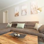A living room with brown sofa, wooden table, and wall art.