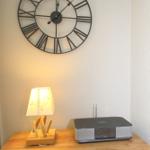 Wooden cabinet with lamp and radio under a wall clock.