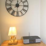 Wooden cabinet with lamp and radio under wall clock