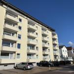 Multi-family building with balconies and parking spaces under blue sky