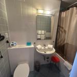 Badezimmer mit Toilette, Waschbecken und Dusche mit Vorhang.