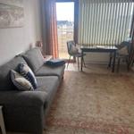 Wohnzimmer mit Sofa, Tisch und Stühlen, Blick auf Balkon mit Blick auf Stadt.