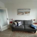 Ein Wohnzimmer mit grauem Sofa, zwei Beistelltischen und einem Wandbild.