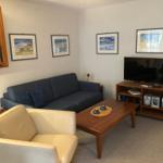 Ein Wohnzimmer mit Sofa, Sessel, Couchtisch und Fernseher.