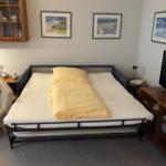 Schlafzimmer mit Bett, Fernseher und Schrank. Wandbilder und Sitzgelegenheit.
