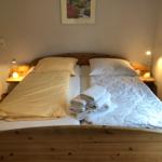 Ein Bett mit Holzgestell, zwei Kissen, Bettwäsche und gefaltete Handtücher.