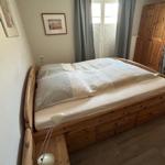 Schlafzimmer mit Holzbett, Vorhängen und Kleiderschrank.
