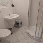 Badezimmer mit Dusche, Waschbecken und Toilette. Fliesenboden und Wandfliesen.