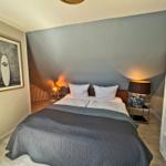 Schlafzimmer mit Bett, Nachttischen und Bücherregal an der Wand.