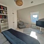 Schlafzimmer mit Bett, Bücherregal, Kleiderschrank, Sessel und TV.