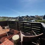 Terrasse mit zwei Stühlen und Tisch, Blick auf Dorf und Leuchtturm.