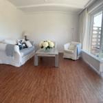 Wohnzimmer mit Sofa, Sessel und Tisch. Holzboden und großes Fenster.
