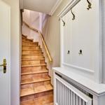 Hausflur mit Treppe, Garderobe und Heizkörper.