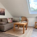 Wohnzimmer mit Sofa, Tisch, Stuhl und TV unter Dachschrägen mit Dachfenster.