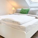 Schlafzimmer mit Doppelbett, Nachttischen und Dachfenster.