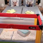 Zimmer mit Doppelbett, Babybett und Waldtapete an der Wand.
