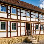 Fachwerkhaus mit rotem Dach und mehreren Fenstern. Eingang mit Treppe.