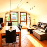 Wohn- und Essbereich mit Sofa, Esstisch und TV. Große Fenster mit Blick.