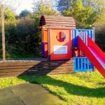 Farbiger Spielplatz mit Rutsche und Klettergerüst im Garten.