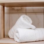 Zwei weiße Handtücher liegen auf einem Holzregal in einem Badezimmer.