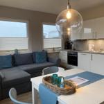 Wohn- und Küchenbereich mit Sofa, Esstisch und moderner Beleuchtung.