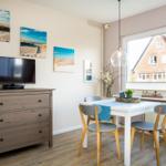 Essbereich mit Tisch, Stühlen und Fernseher. Fensterblick auf ein Haus.