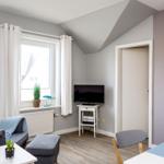 Wohnzimmer mit Sessel, Fernseher und Fenster. Wand mit Strandregeln.