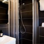 Duschkabine mit Duschbrause, Waschbecken und Toilette in modernem Badezimmer.