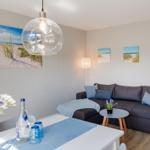 Wohnzimmer mit Sofa, Tisch und Wandbildern von Strand