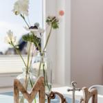 Holz-Schild mit Anker und Blumen in Glasflaschen auf Tisch