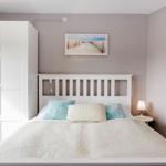 Schlafzimmer mit weißem Bett, Kleiderschrank und Wandbildern