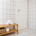 Badezimmer mit Toilette, Holzbank und gefalteten Handtüchern.