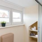Bathroom with shower, toilet, and window with plant.