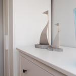 Two sailboats and a blue glass vase on a white dresser.