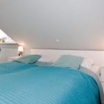 Bedroom with bed, nightstands, and lamp under sloped ceiling