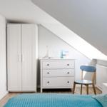 Bedroom with sloped ceiling, white dresser, chair, and bed with blue bedding.