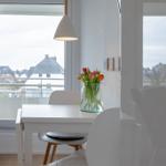 Essbereich mit weißem Tisch, Stühlen und Blumen in Glas. Fenster mit Blick auf Wohngebiet.