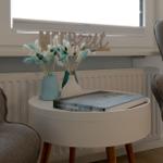 Runder Tisch mit Büchern und Vasen vor Fenster