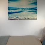 Ein Bett mit Bettwäsche und Wandbild mit Meeresmotiv.