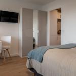 Schlafzimmer mit Bett, Schreibtisch, Kleiderschrank und Fernseher.