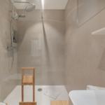 Dusche mit Glaswand, Holzstuhl und Waschbecken
