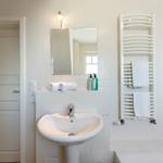 Badezimmer mit Waschbecken, Spiegel, Handtüchern und Heizkörper
