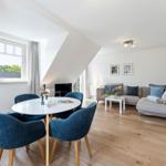 Wohnbereich mit Essplatz, Sofa und Holzboden unter schrägen Dachdecken.