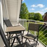 Balkon mit Tisch und Stühlen, Blick auf Grünfläche und Haus.